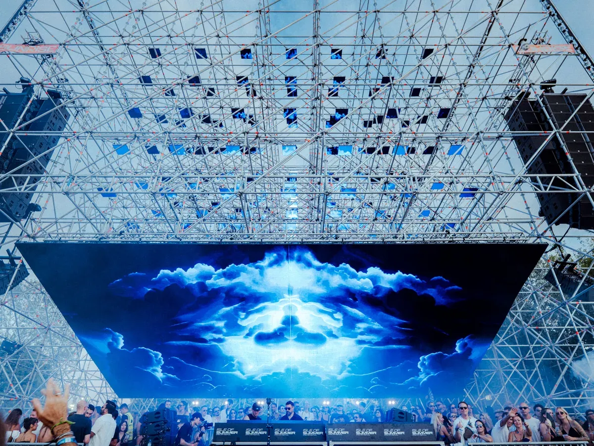 Sunrise Stage by day from below the 7 × 7 × 5 LED matrix, cloud content on the main screen, Isle of Summer Vienna 2026